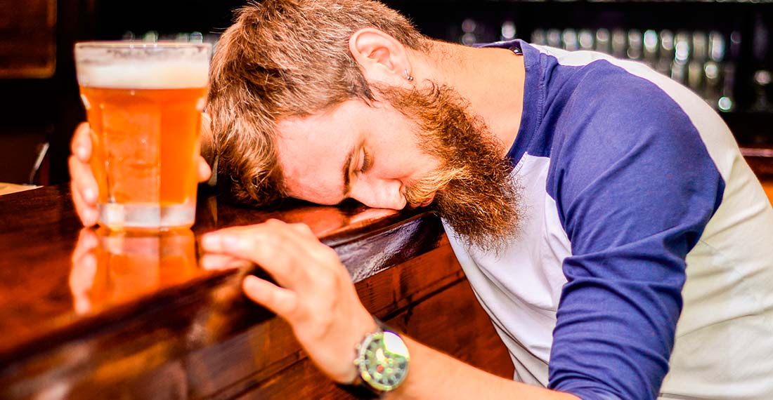 мужчина с кружкой пива спит за барной стойкой