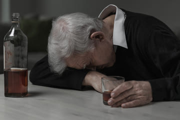 мужчина лежит на столе с стаканом в руке